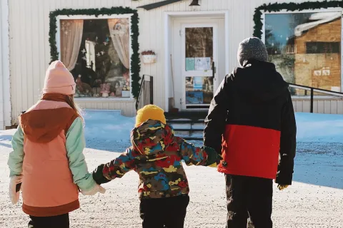 Barn som håller varandra i handen och går mot en butik 
