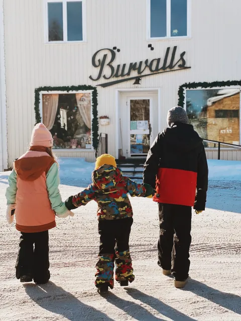 Barn som håller varandra i handen och går mot en butik 